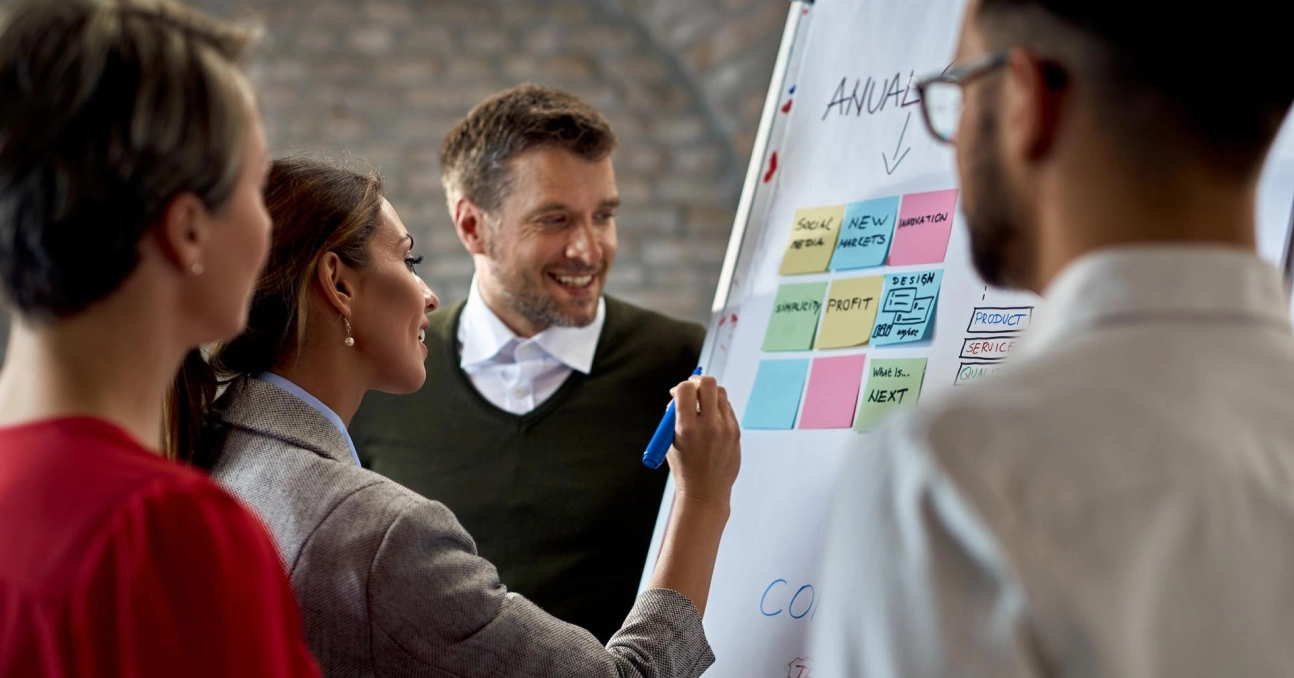 Team brainstorming with sticky notes on a whiteboard during a business meeting in a modern office setting.