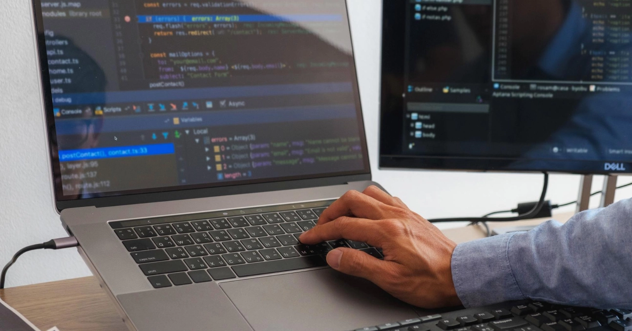 Person coding on a laptop with programming interface on the screen.